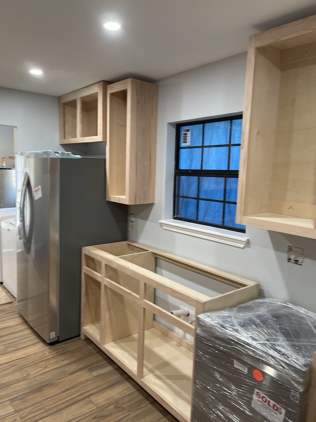 Renovated kitchen with cabinetry, stone counters, and wood-look flooring